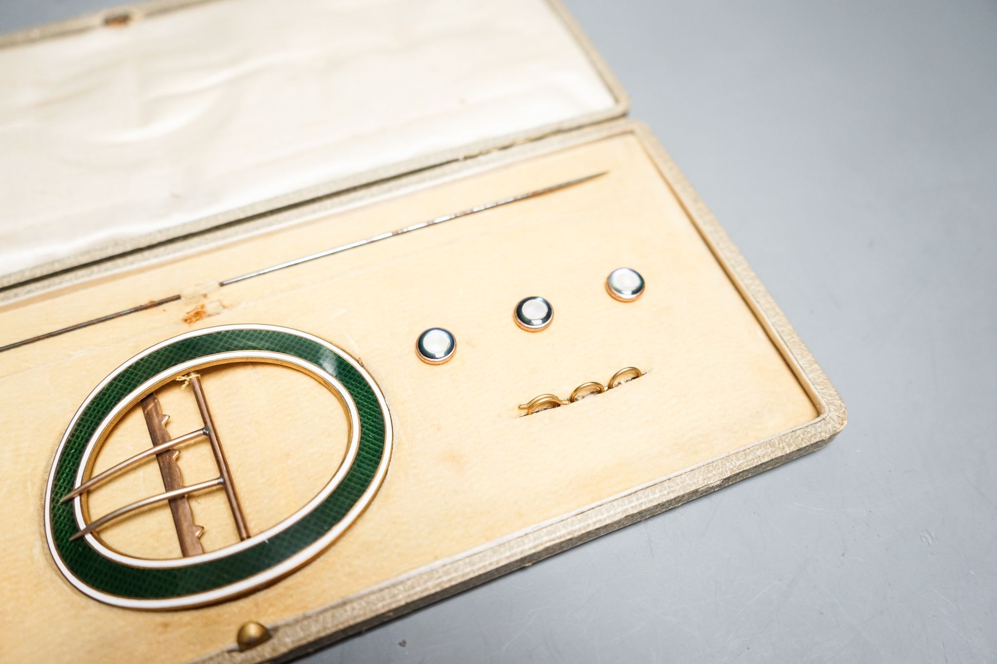 An early 20th century cased gilt metal and enamel buckle, buttons and hat pin set, case 30cm